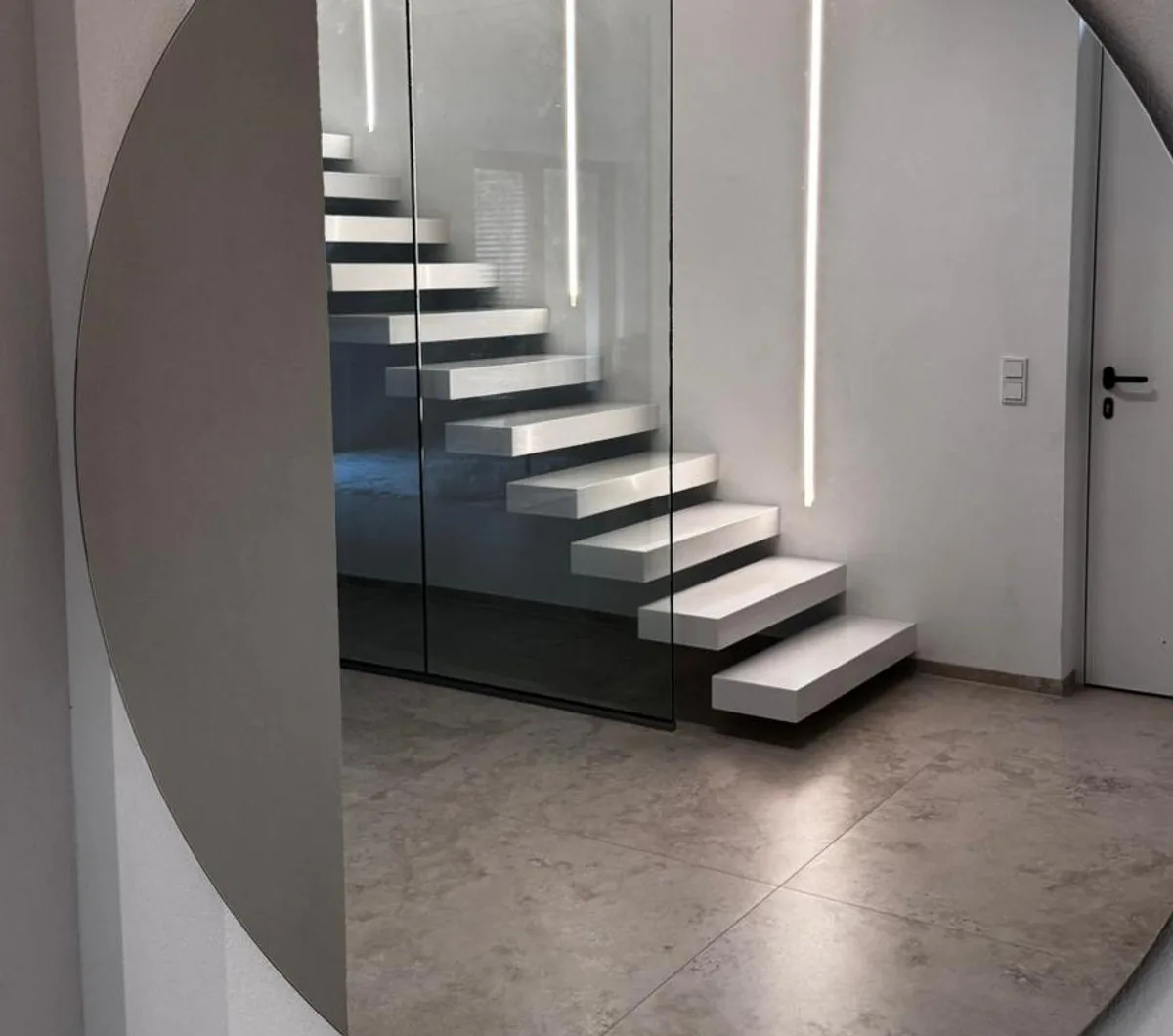 Raumhohe Glaswand als Absturzsicherung neben einer freitragenden Treppe mit weißen Stufen, Ottweiler